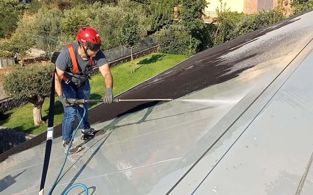 Tecnico Etnya con casco lava il tetto di una villa coperto di cenere a Trecastagni
