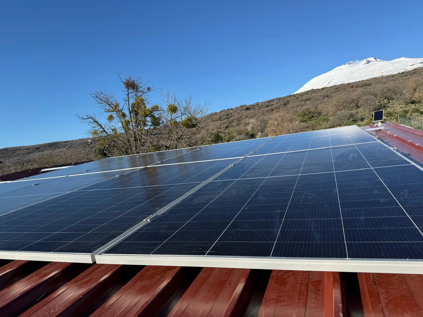 Impianto fotovoltaico con l'Etna innevato sullo sfondo